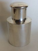 A small cylindrical silver tea caddy with lift-off