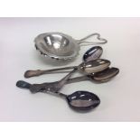 Four silver teaspoons together with a strainer. Ap