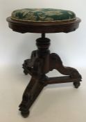 A mahogany circular piano stool on three spreading