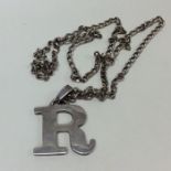 A silver medallion in the form of the letter "R".