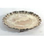 An early 20th century silver salver of circular form with piecrust border on three scrolled feet,