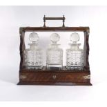 A Victorian oak three bottle tantalus with a silver plated handle and mounts, w.