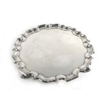 A Victorian silver salver of circular form with piecrust border on four scrolled feet,