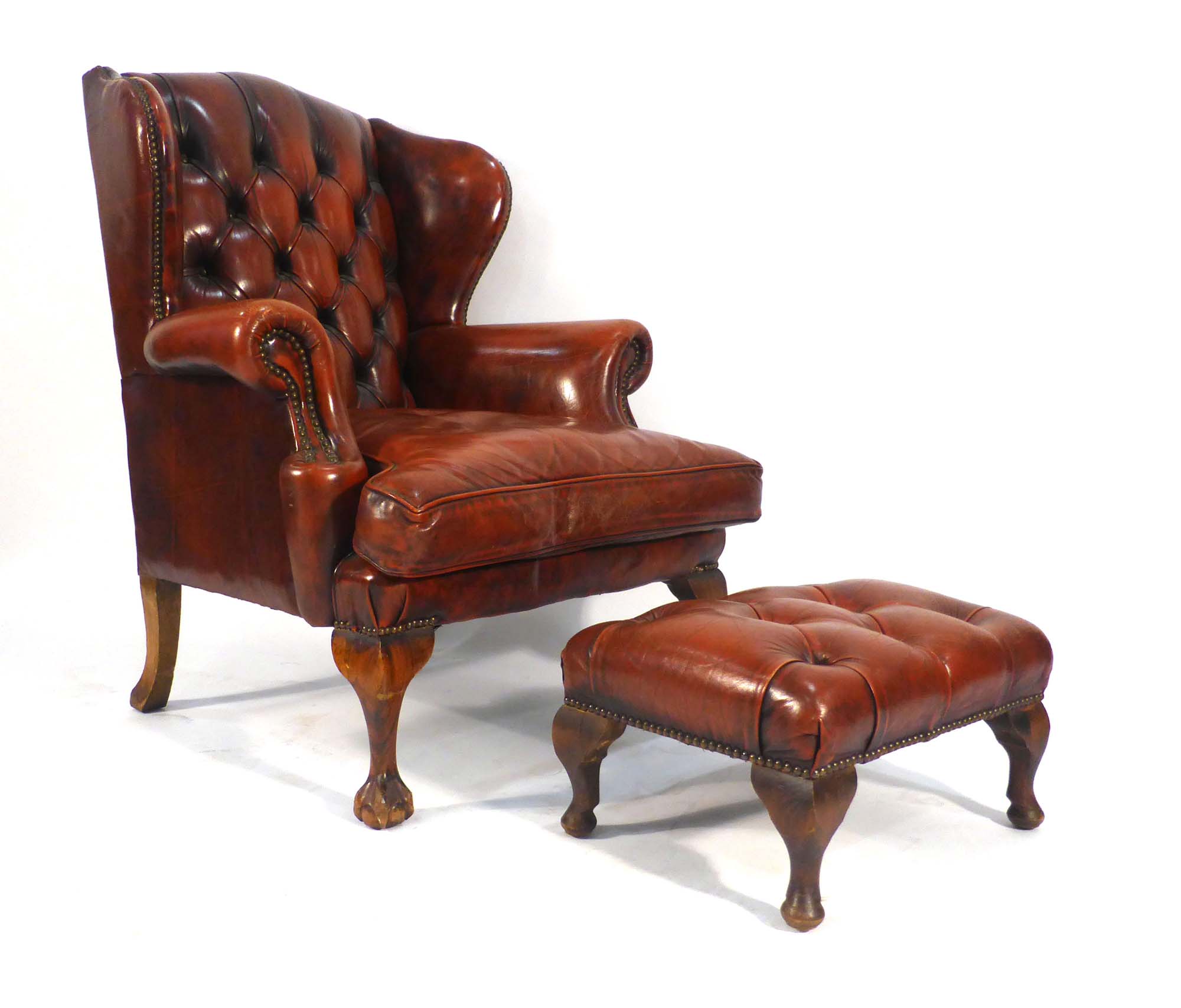 A late 20th century red leather and button upholstered wingback armchair on ball and claw feet,