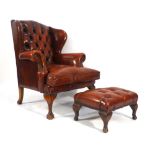 A late 20th century red leather and button upholstered wingback armchair on ball and claw feet,