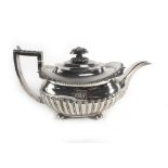 A George III silver teapot of boat shaped form having foliate and gadrooned decoration on bun feet,