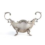 A late Victorian Scottish silver two handled dish of boat shaped form raised on four outswept feet,