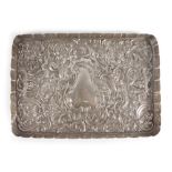 An Edwardian silver and repousse decorated tray of rectangular form having a vacant cartouche,