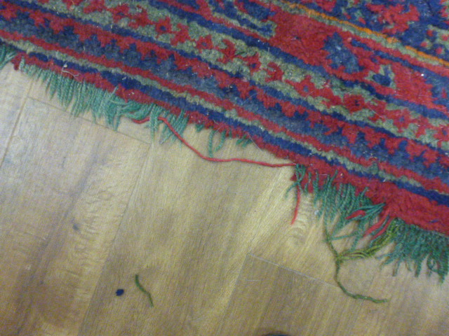 An early 20th century red ground rug with repeated motifs within red and blue bands, - Image 5 of 8