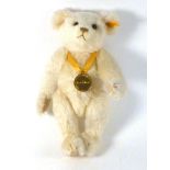 A modern Steiff fully jointed bear in blonde mohair and suspending a medallion from the Danbury