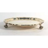 An early 20th century silver salver of circular form with piecrust border on three scrolled feet,