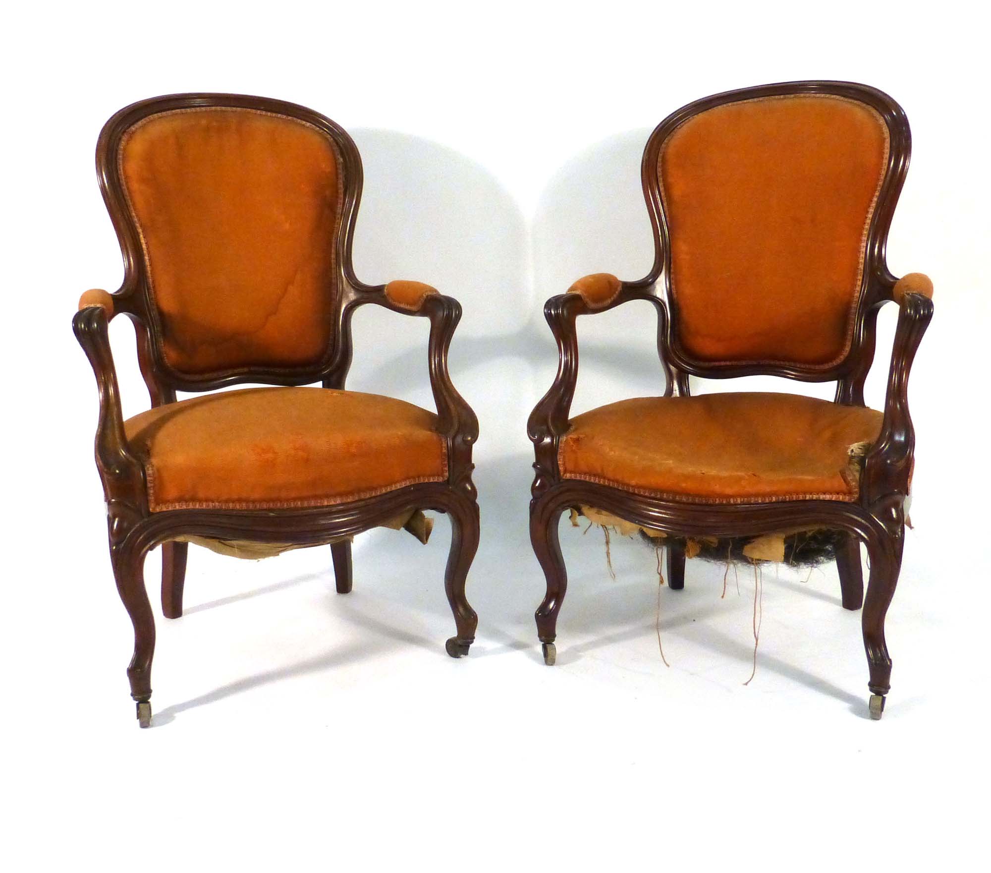 A pair of 19th century French mahogany and upholstered open armchairs on cabriole legs with castors