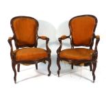 A pair of 19th century French mahogany and upholstered open armchairs on cabriole legs with castors