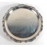 An early 20th century silver salver of circular form with piecrust border on three claw and ball