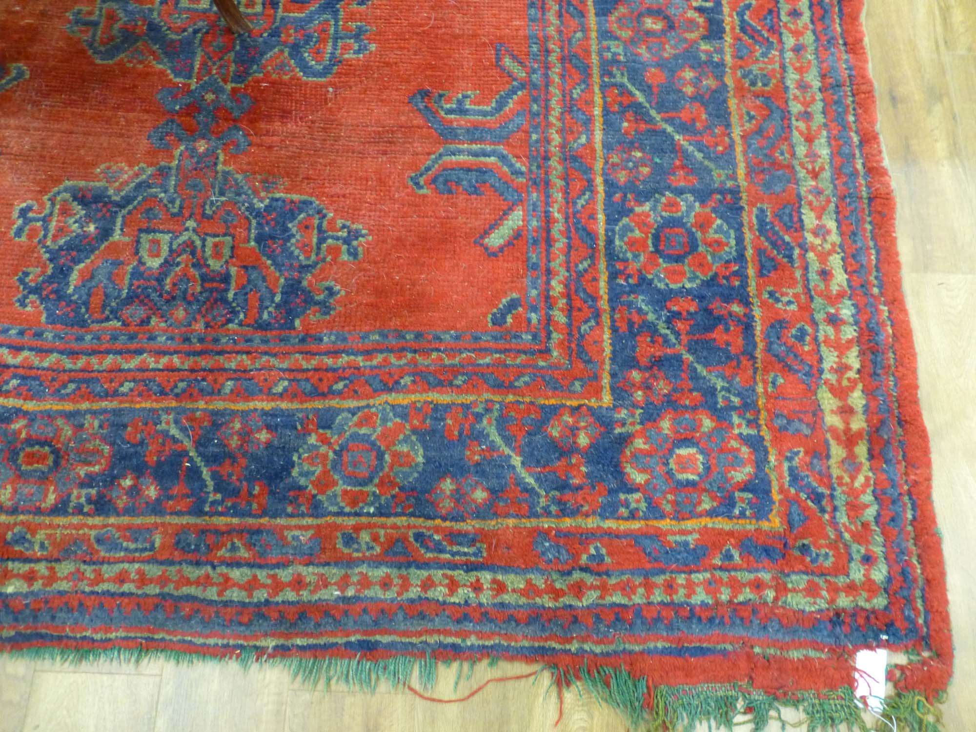 An early 20th century red ground rug with repeated motifs within red and blue bands,