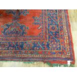 An early 20th century red ground rug with repeated motifs within red and blue bands,