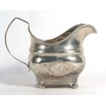 A 19th century Irish silver milk jug of boat shaped form with bright cut engraving on four bun feet,