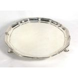 An early 20th century silver salver of circular form with capped piecrust border on three outswept