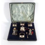 An early 20th century cased condiments set containing seven silver cruets of vase and square form,