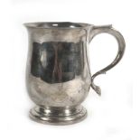 An early 20th century silver tankard of bellied form with c-scroll handle on a circular foot,