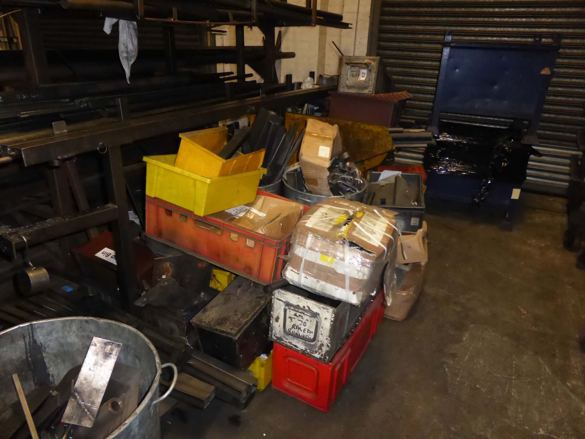 Yellow metal forklift tipping skip on castors along with a pallet of scrap metal and 2 blue