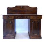 A Victorian mahogany twin pedestal sideboard with a scrolled back over three drawers and two doors