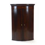 A George III mahogany, strung and inlaid bow-fronted hanging corner cupboard with two doors, w.