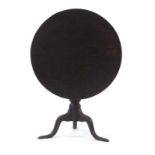 An 18th century oak tilt-top table, the circular surface on a turned column with three splayed legs,