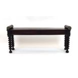 An early 19th century mahogany window seat with brass rose capped sides over bobbin turned supports