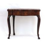 An early 18th century walnut and crossbanded tea table with a folding top and bow-fronted frieze
