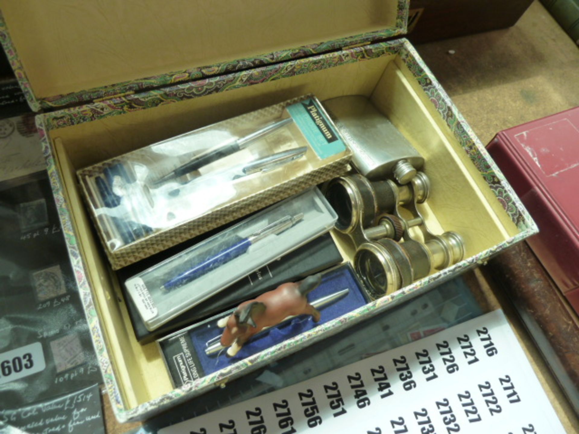 Box containing opera glasses, hip flasks and various pens