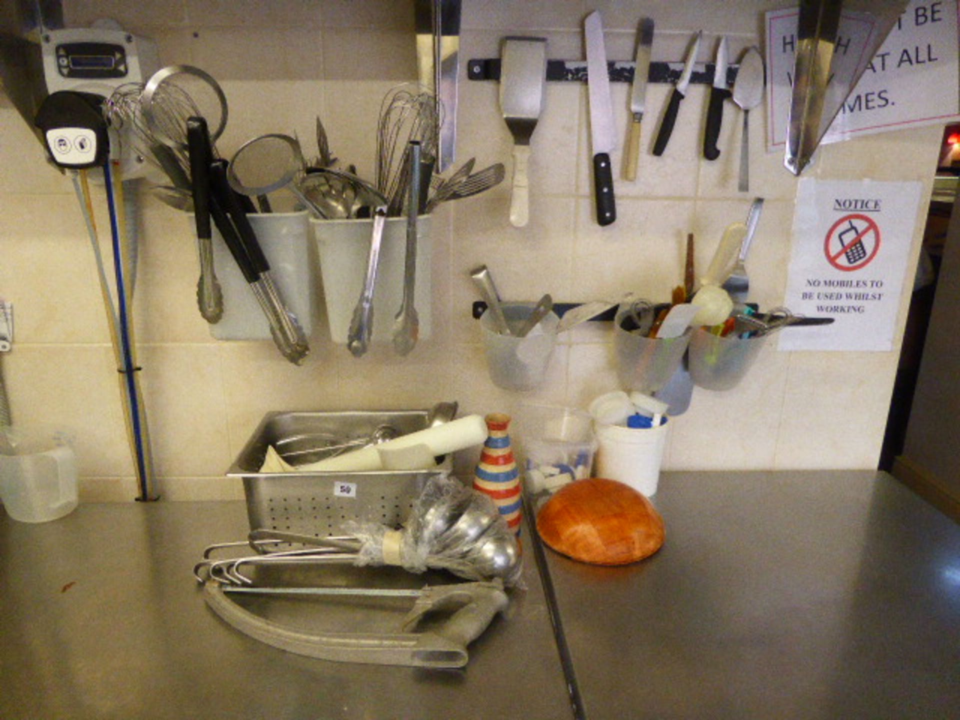 Range of utensils in dish wash area including serving tongs, whisks, pasta spoons, slotted spoons,