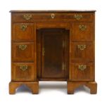 A George II figured walnut and crossbanded kneehole desk with an arrangement of seven drawers,