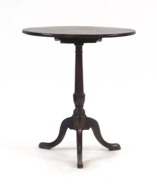 An 18th century oak tilt-top table, the circular top on a turned column,