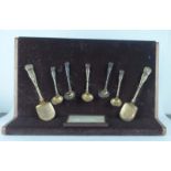 A presentation stand displaying a suite of George IV silver gilt Kings pattern flatware