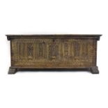A 19th century walnut coffer, the lid overhanging a dental-type cornice and seven carved panels,