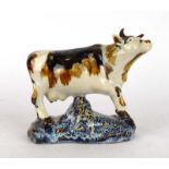 A studio pottery figure modelled as standing cow, h. 12.