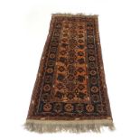 A mid-20th century woolen rug, the salmon ground with medallions and motifs within blue bands,