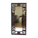 A late 19th/early 20th century Chinese hardwood wall mirror of rectangular form, typically carved,