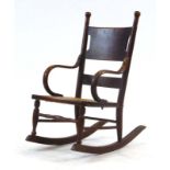 A late 19th/early 20th century oak child's rocking chair with bentwood arms and a bergere seat