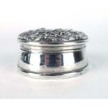 A silver ring box of circular form, the cover repousse decorated with c-scrolls and birds,