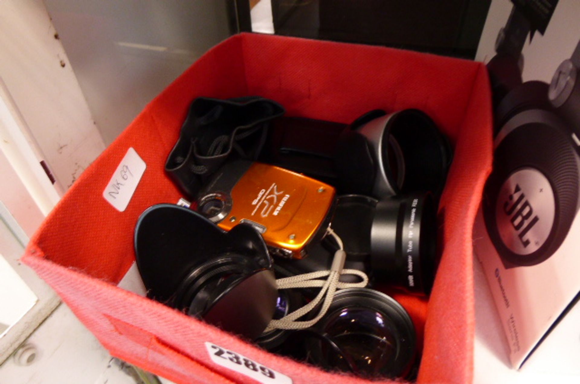 Red tray containing loose camera lenses and digital cameras