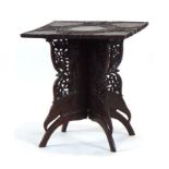 A Middle Eastern foliate carved hardwood table, the square top resting on a four-panel folding base,