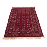 A 20th century woolen Tekke-type rug, the red ground with medallions within matching bands,