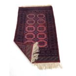 A Tekke-type rug, the pale red ground with ten medallions within matching bands,