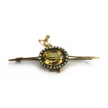 A late 19th/early 20th century yellow metal bar brooch set oval citrine within a border of small