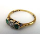 An early 20th century 18ct yellow gold ring set diamond and two emeralds in rubover settings,