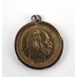 A yellow metal pendant suspending a 5 mark coin dated 1877 in a loose mount,