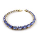 A 10ct yellow gold tennis-type bracelet set twenty-six oval tanzanite,