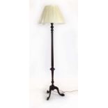 A Victorian mahogany turned standard lamp on a tripod base with a new pleated shade